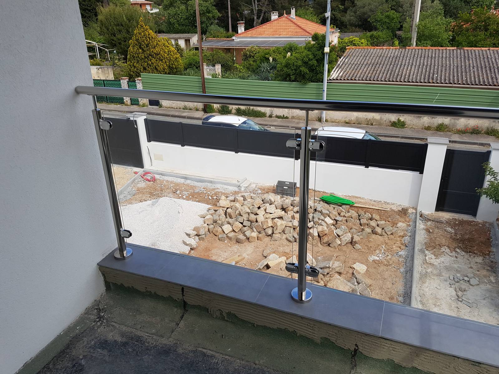 Rambarde en tube rond poli et verre entourant le balcon de la maison.