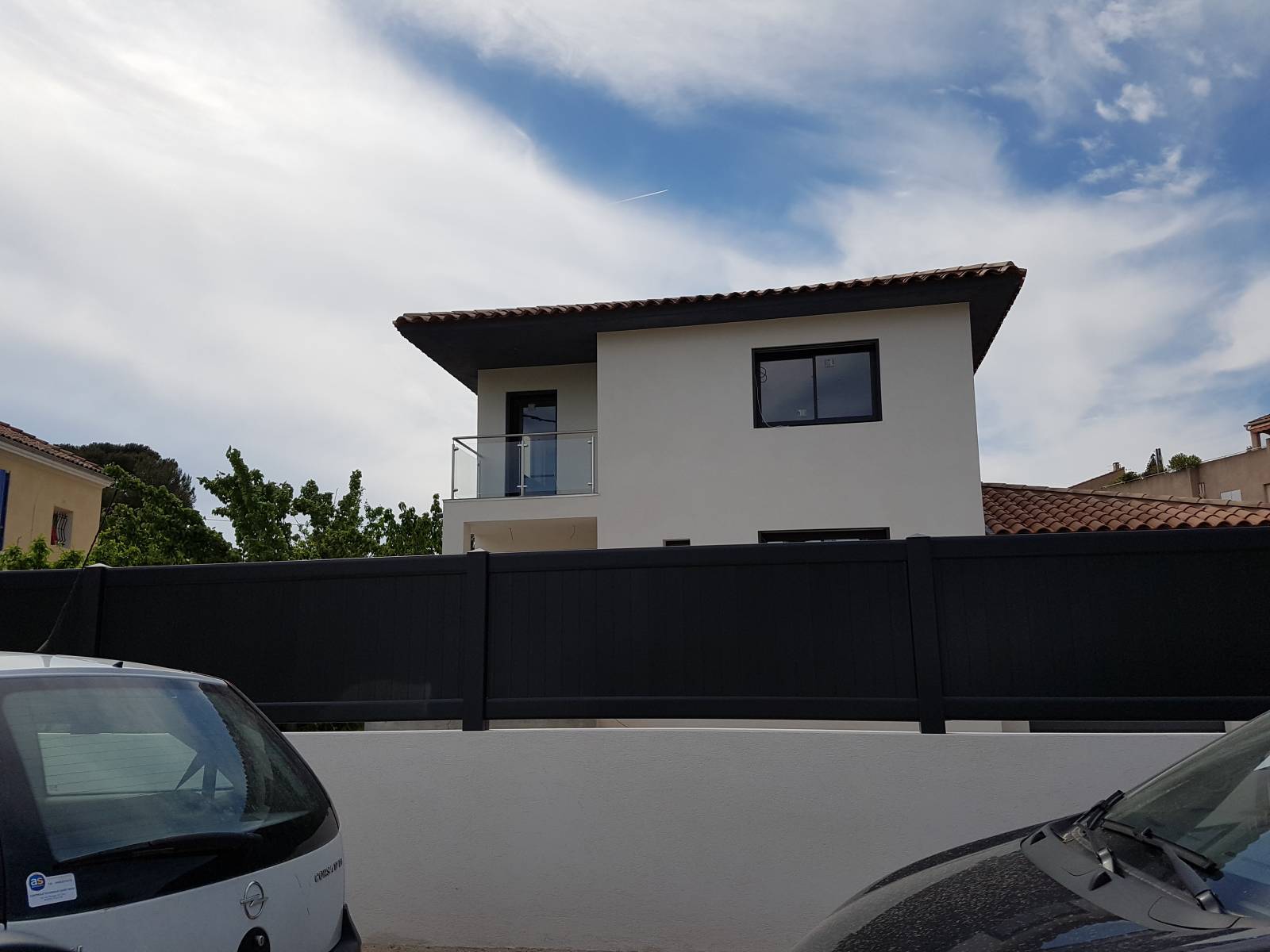Vue de la maison moderne avec rambarde en inox et verre, mettant en valeur l'architecture contemporaine.