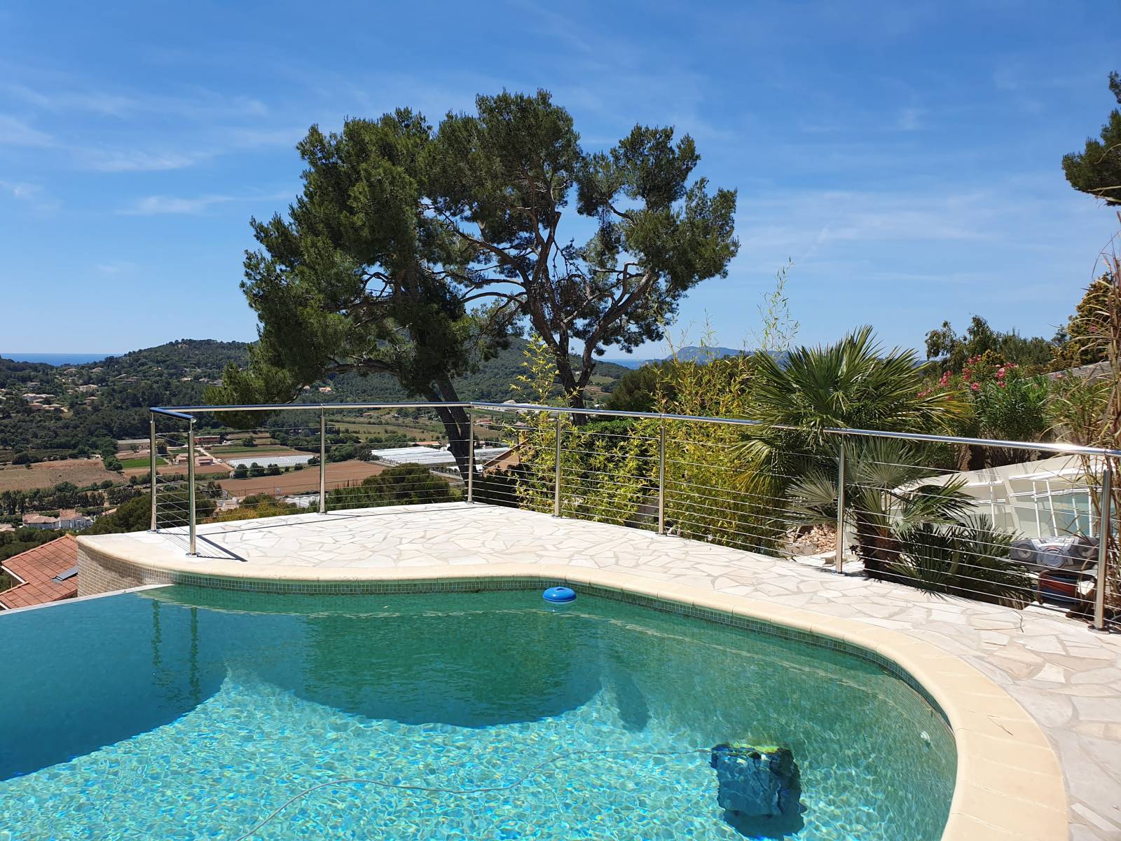 Terrasse moderne à La Farlède entourée d'un garde-corps en inox, surplombant la piscine.
