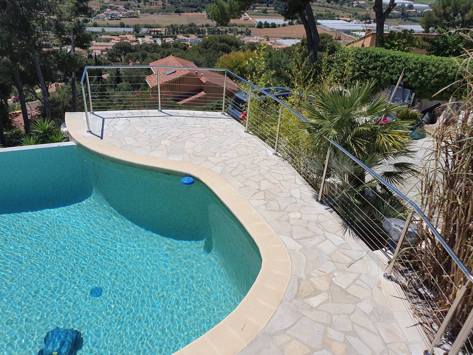 Vue d'une piscine à La Farlède, entourée d'un garde-corps en inox poli.
