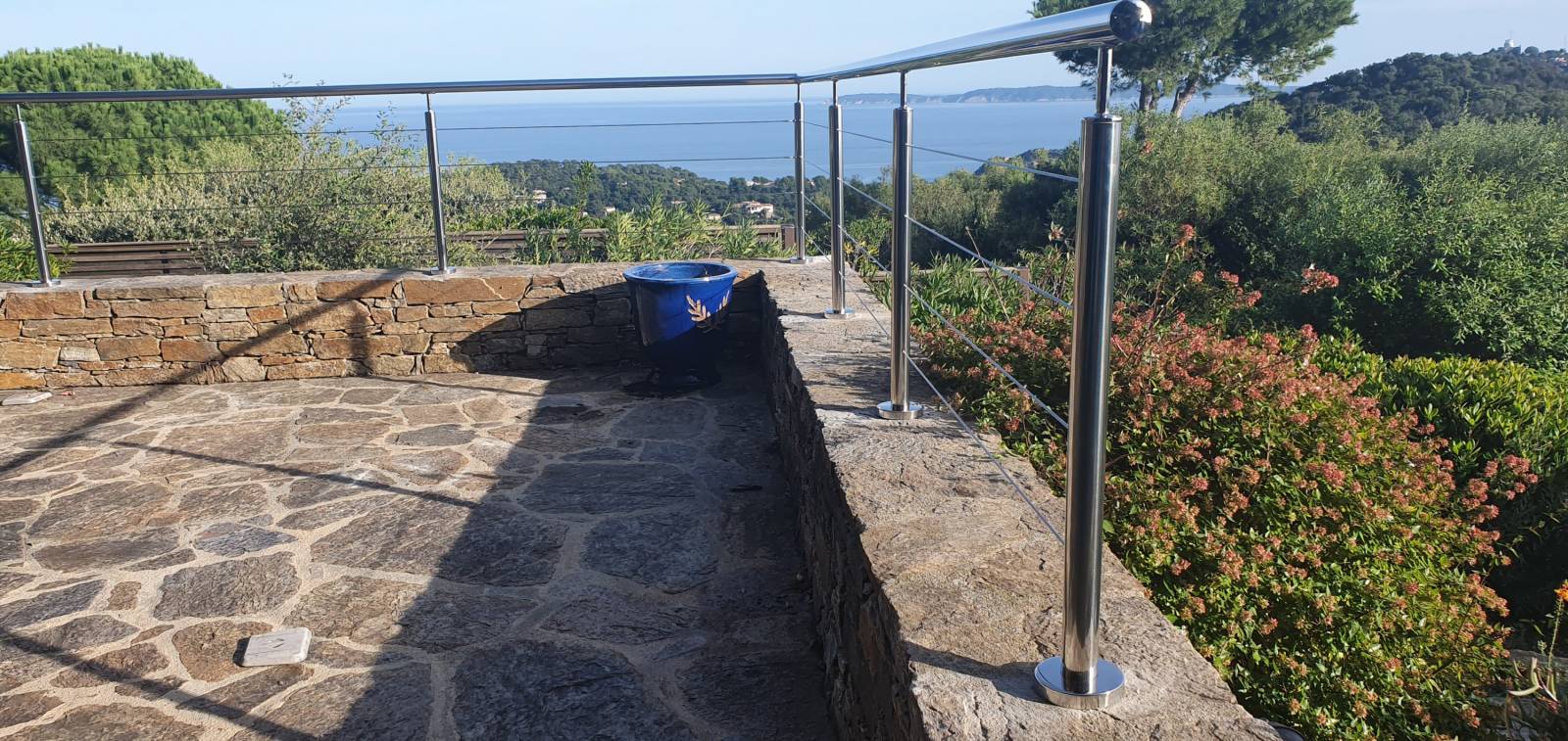 Terrasse vue mer entourée d'un garde-corps en inox avec verdure autour