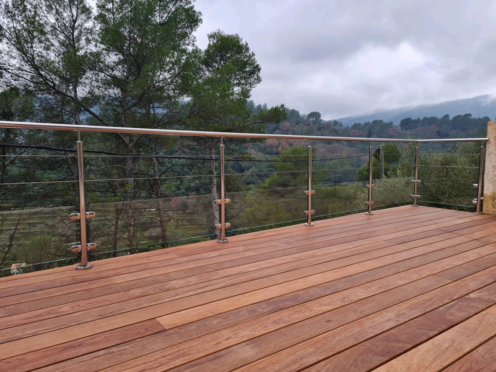 Vue d'ensemble de la terrasse rénovée à Solliès-Toucas, équipée d'une rambarde en inox poli miroir avec verre en soubassement et câbles en inox.
