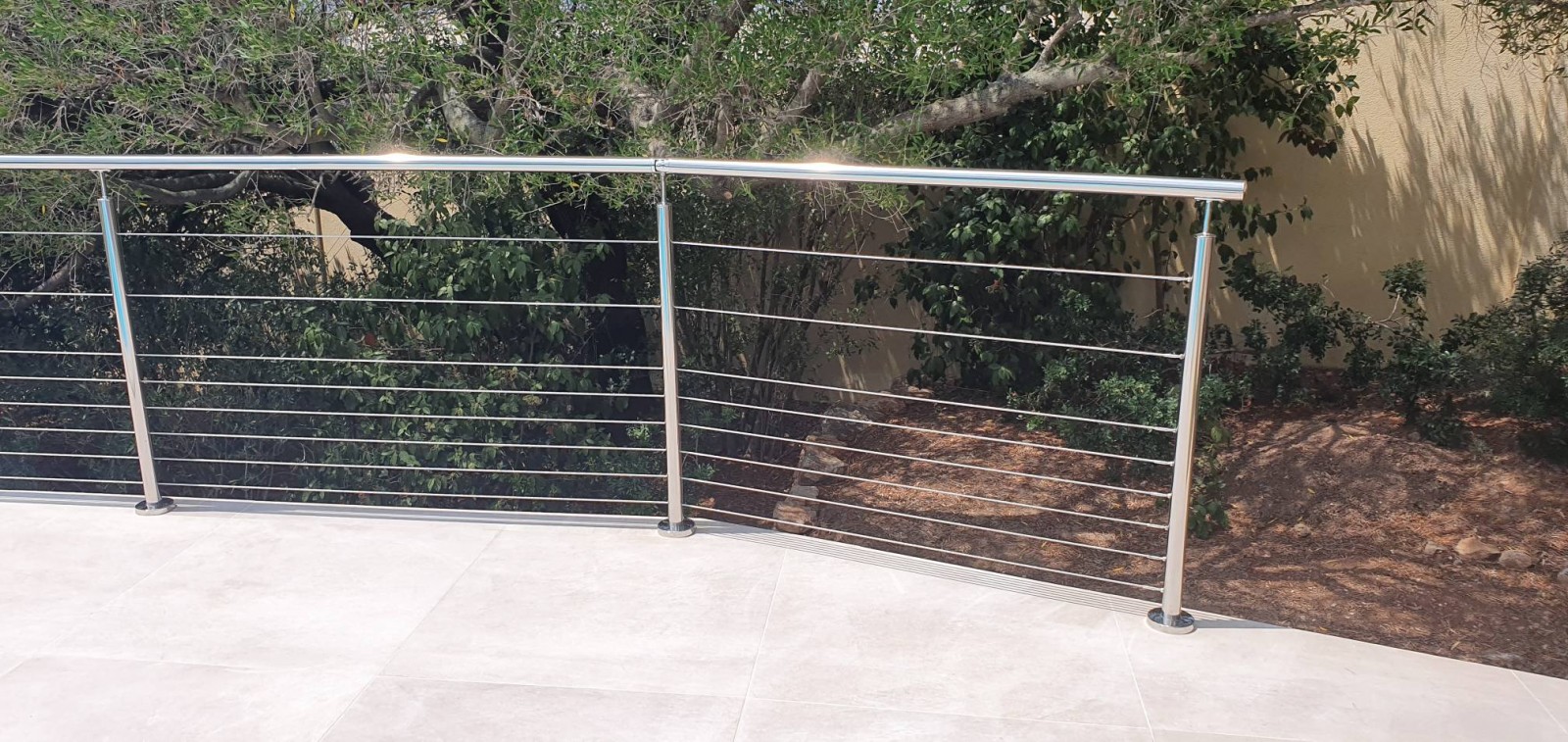 Fixation à la française des poteaux en inox sur un carrelage épais, réalisée avec une carotteuse diamant pour éviter toute casse.