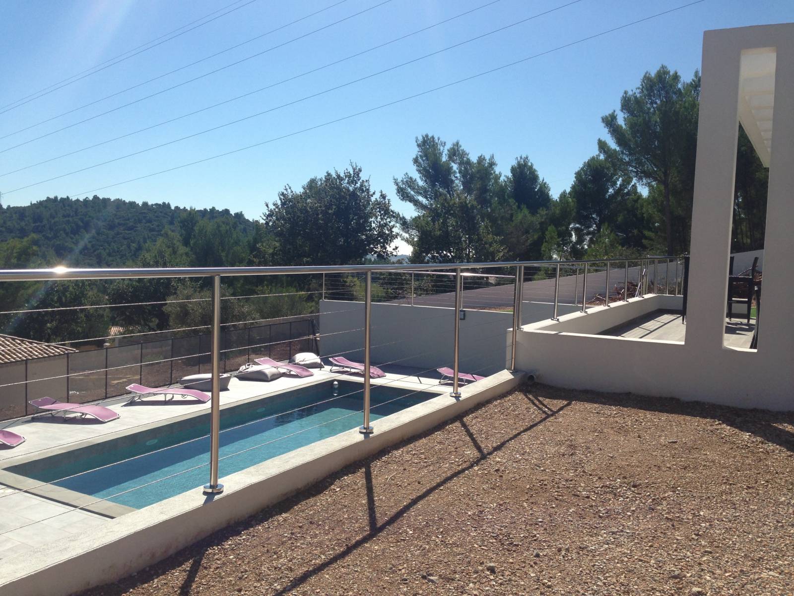 Vue rapprochée d'un garde-corps en inox poli sur une terrasse à La Farlède avec vue sur piscine.