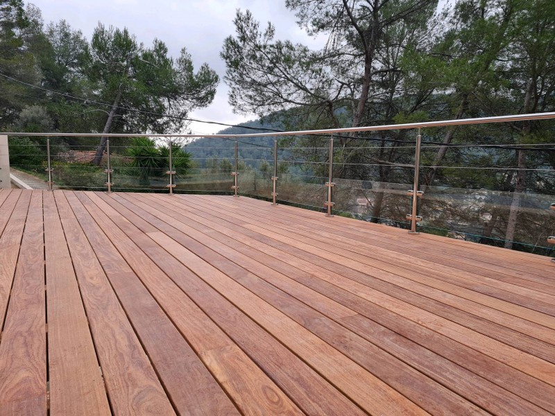 Zoom sur la rambarde en inox 316L poli miroir, avec panneaux de verre maintenus par des pinces en inox pour sécuriser la terrasse.