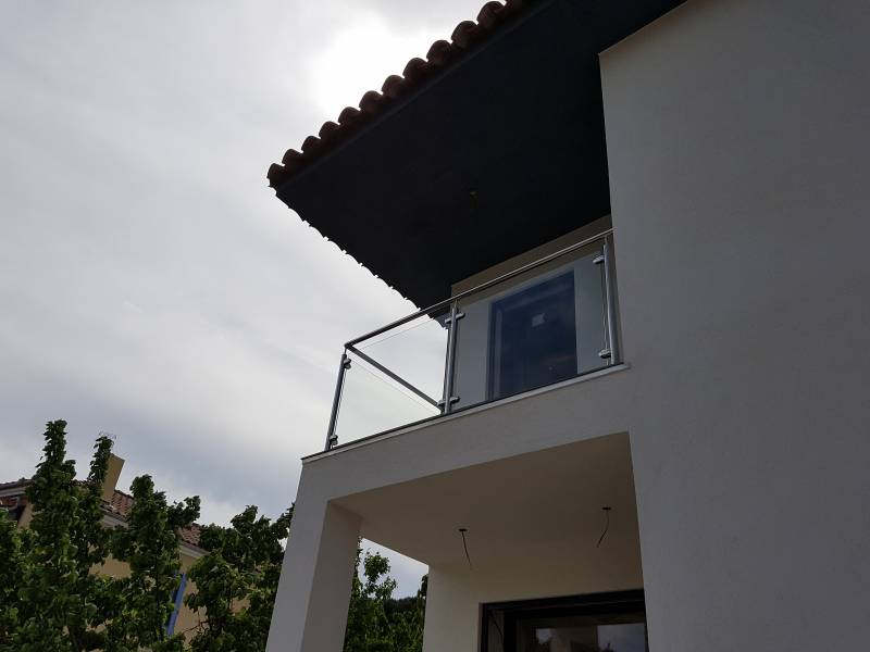 Vue de la maison moderne avec rambarde en inox et verre, mettant en valeur l'architecture contemporaine.