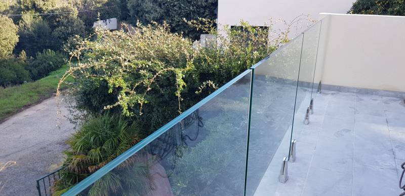 Garde-corps en verre trempé soutenu par des pinces en inox, offrant une vue dégagée et un design épuré.