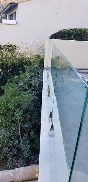 Garde-corps en verre clair trempé maintenu par des pinces en inox, offrant un design moderne et une sécurité optimale.