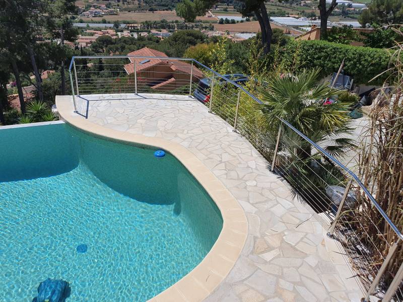 Vue d'une piscine à La Farlède, entourée d'un garde-corps en inox poli.