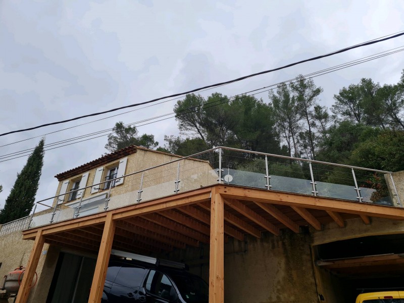 Perspective de la terrasse donnant sur l’extérieur, avec une rambarde en inox et verre intégrée à l’architecture contemporaine de la maison.