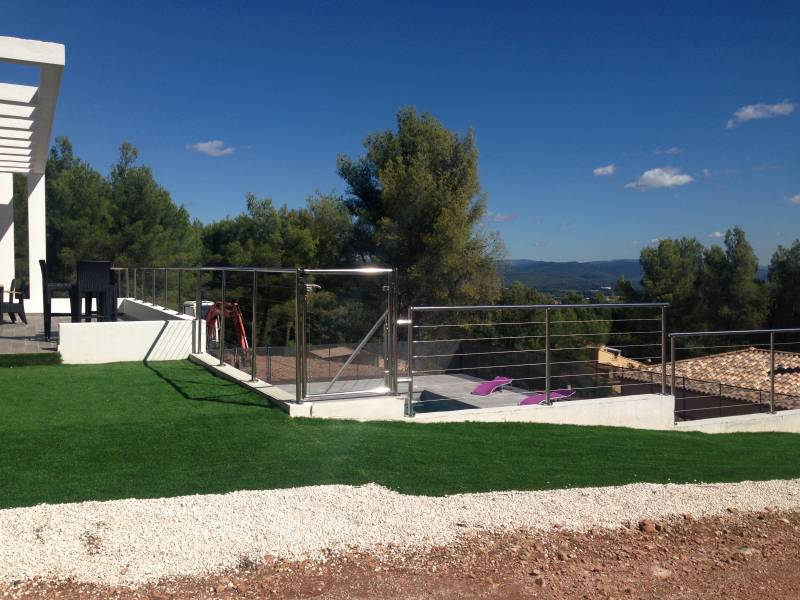 Garde-corps en inox et verre installé sur une terrasse à La Farlède, avec vue sur le jardin.