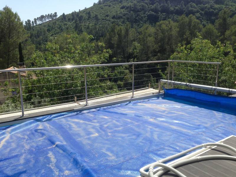 Vue d'ensemble d'une piscine avec rambarde en inox et poteaux fixés au sol.