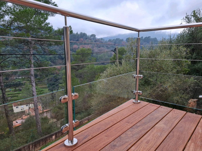 Détail des fixations en inox poli miroir, montrant les pinces retenant le panneau de verre pour une finition élégante et sécuritaire.