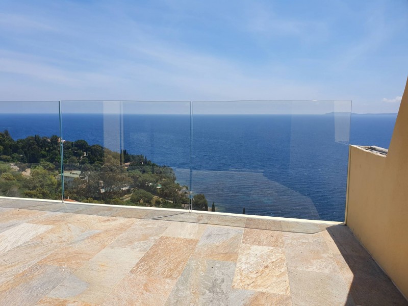 Détail d'une maison avec garde-corps en verre extra clair, bénéficiant d'une vue spectaculaire sur la mer.